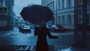 Woman in black coat holding an umbrella in the rain.