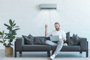 Man sitting on couch with ductless AC system