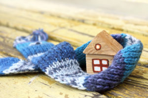 Small wooden home wrapped in a knitted scarf.