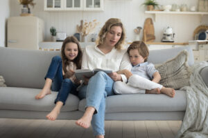 mother and children sit on sofa reading book