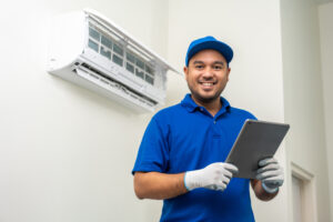 Technician in uniform using tablet to check list of maintenance and cleaning filters of ductless system. 