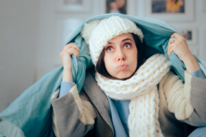 cold woman wearing winter clothing and blanket indoors