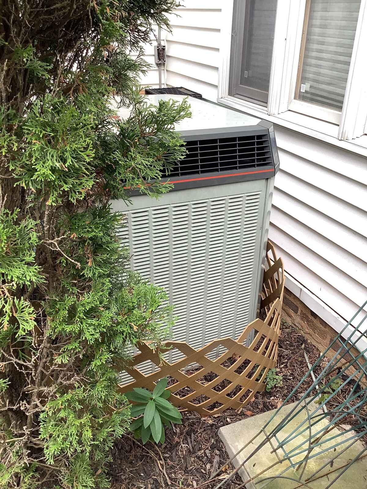 Outdoor AC Compressor surrounded by shrubbery