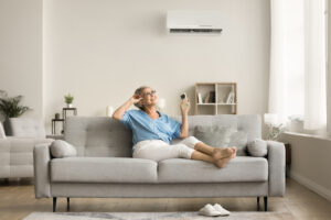 Happy relaxed woman holding AC remote control