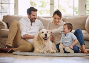 young family sitting on the living room floor with their dog