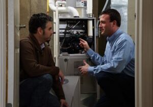 Training technician shows man the inside of hvac system